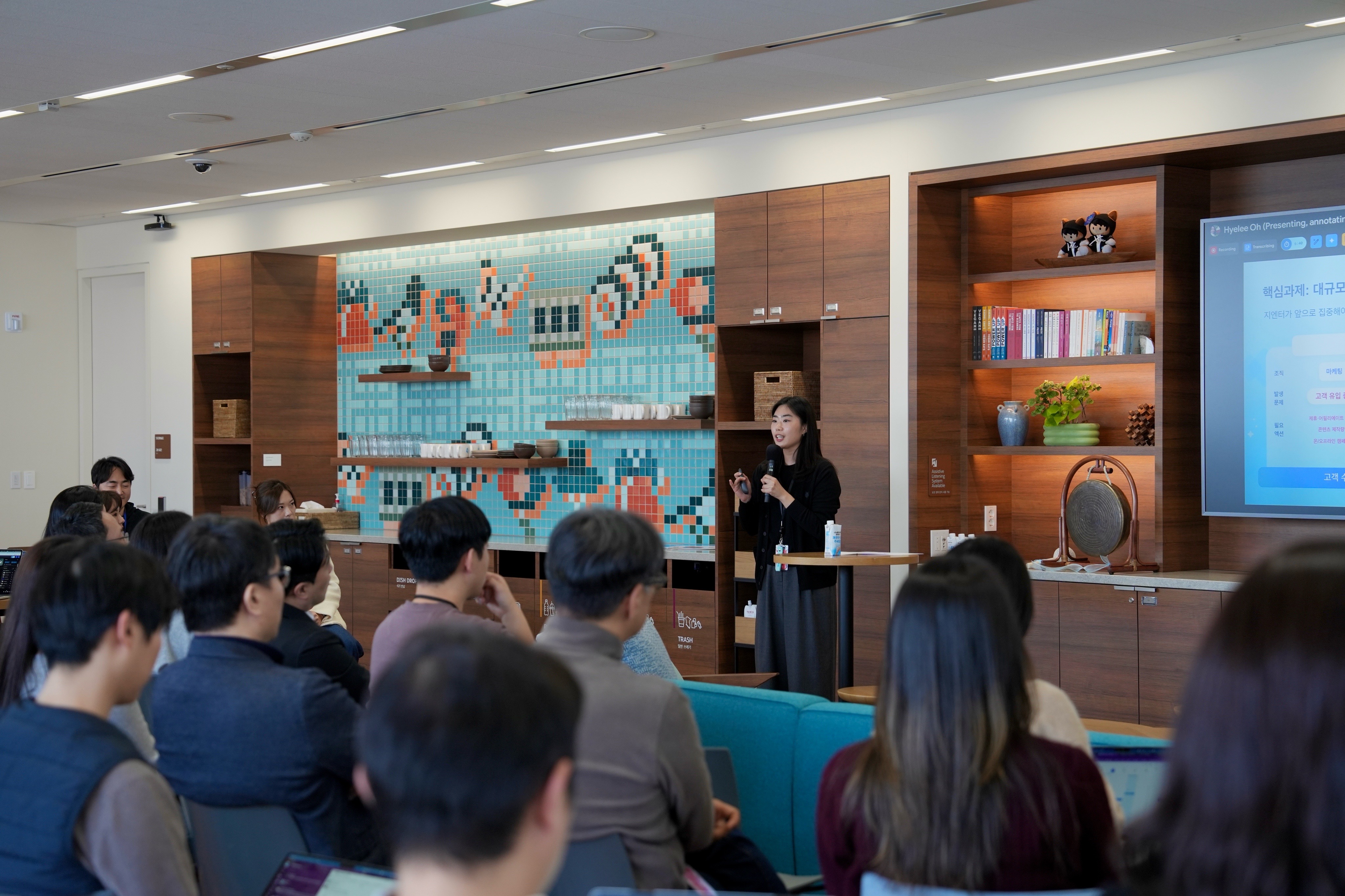woman presents in a modern office space to an active audience
