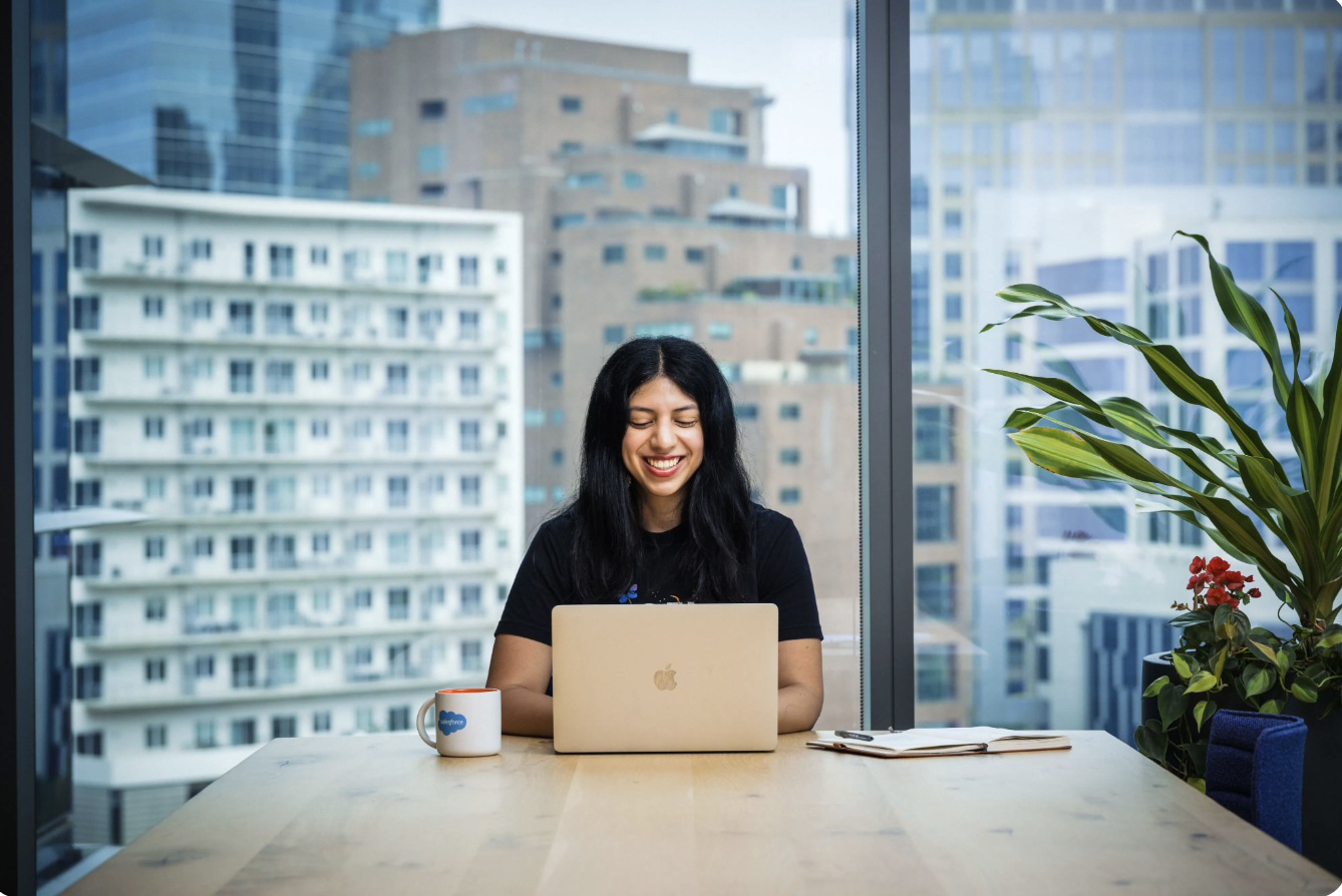 A woman sits in a modern office space in front of a computer