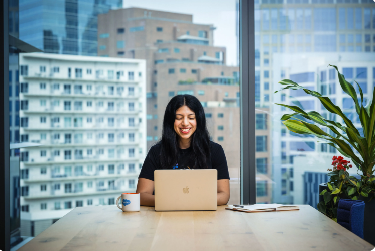 A woman sits in a modern office space in front of a computer