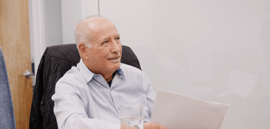 man sits in an office, engaged in a discussion with someone off camera
