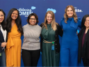 group of six women stand against a trailblazing women background