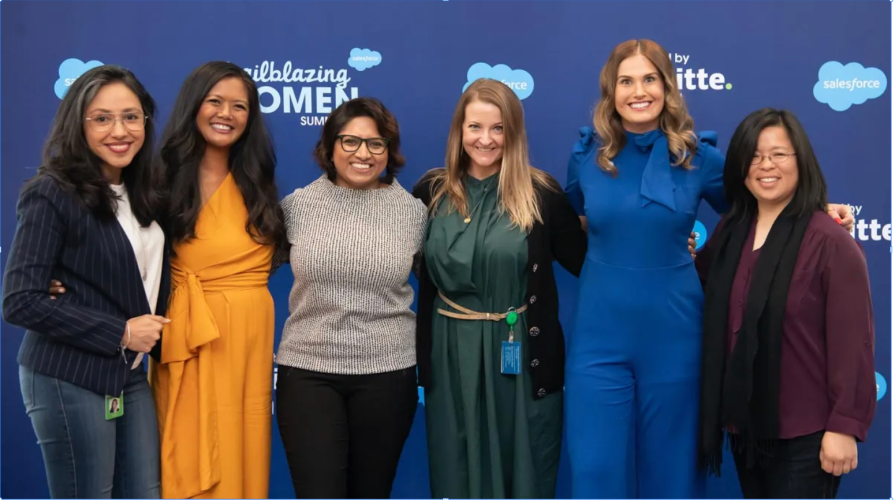 group of six women stand against a trailblazing women background