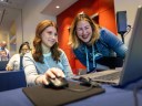 Salesforce Connections event showing a woman getting hands-on experience with a Salesforce admin to build marketing campaigns and workflows with AI and automation.
