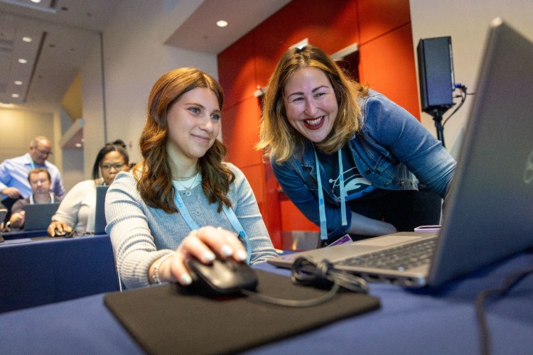 Salesforce Connections event showing a woman getting hands-on experience with a Salesforce admin to build marketing campaigns and workflows with AI and automation.
