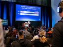 A speaker on stage at a Salesforce event presenting a slide about the common failures of AI agents to understand human context.