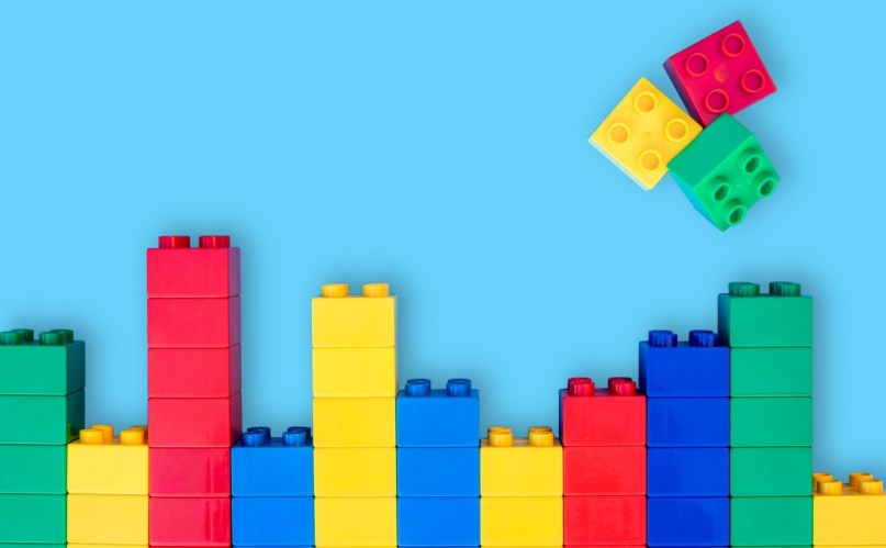 Bar graphs plastic building blocks toy bricks on blue background.