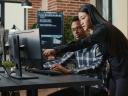 Two colleagues review information on a computer monitor in a modern office.