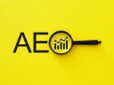 Illustration of AEO font on yellow background with a magnifying glass.
