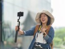 Asian woman vlogging with smartphone on selfie stick for travel content