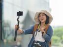 Asian woman vlogging with smartphone on selfie stick for travel content
