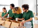 charity, donation and volunteering concept - international group of happy smiling volunteers packing food in boxes