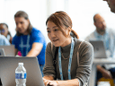 Close-up of an attendee focused on her laptop screen in a collaborative Dreamforce setting.