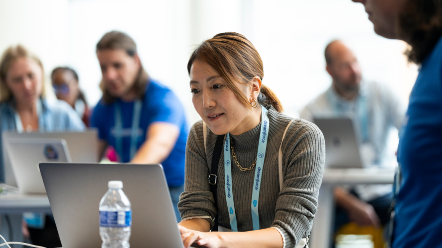 Close-up of an attendee focused on her laptop screen in a collaborative Dreamforce setting.