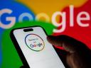 Closeup of a person holding a smartphone displaying a review us on google logo against a colorful background