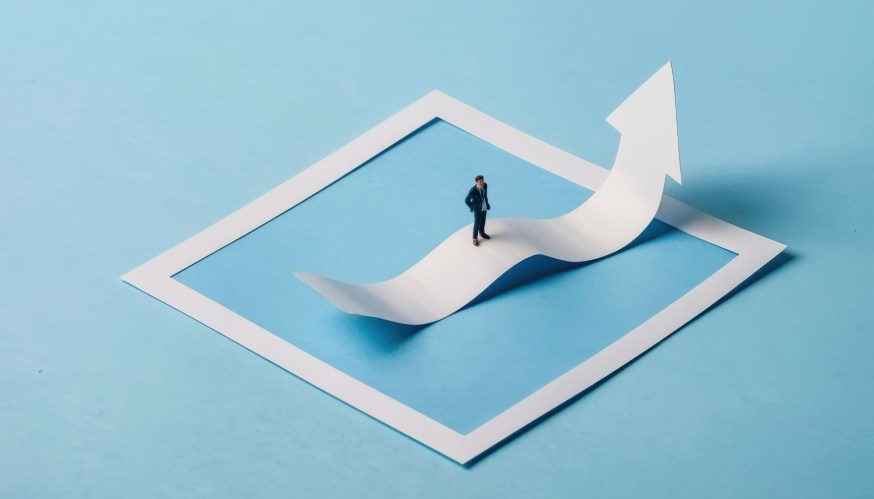 Confident businessman standing on a rising arrow representing corporate growth financial success and market progress