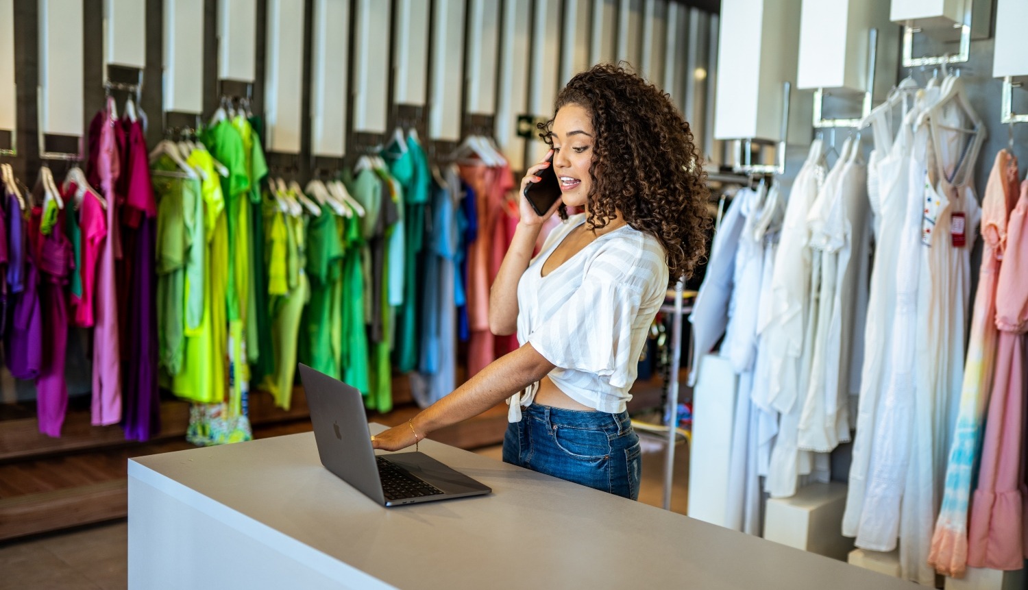 Smiling Latin designer contacts client about online order in fashion shop.