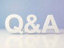 Three-dimensional white q and a letters standing on a reflective white surface against a soft purple and blue gradient background, clean studio light