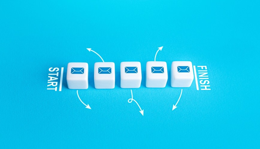 Five white dice with blue email icons on them in a row like a start and finish line. Blue background.
