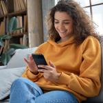 Cliente sorri enquanto olha para o smartphone.