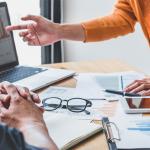 Executivos em reunião analisam gráficos de desempenho e dados computados da empresa.
