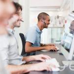 Consultores de pós-vendas sentados em uma bancada realizando atendimentos ao cliente via computador.