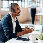 Profissional gatekeeper de vendas está ao telefone, ele sorri e usa fones para conversar.