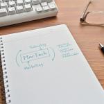Imagem de um caderno sobre uma mesa com a inscrição MARTECH no centro e as palavras technology e marketing em volta.