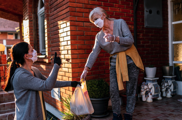 Woman handing older woman groceries