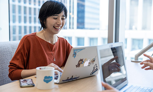 Mai laughing and working on a laptop