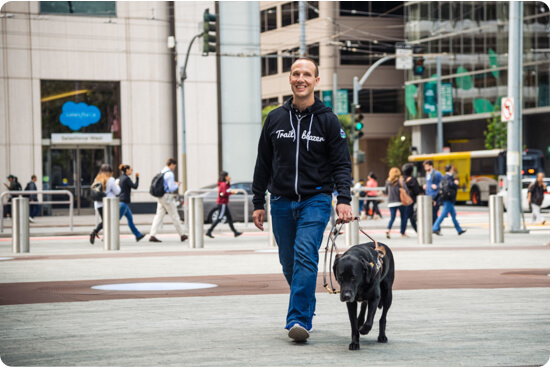 Adam Rodenbeck walking across the street with his guide dog