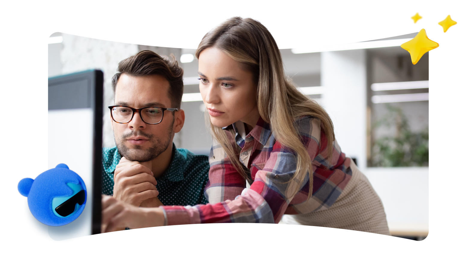 A man and a woman are intently looking at a computer monitor in an office setting. The man is seated, wearing glasses and a dotted shirt, resting his chin on his clasped hands. The woman is standing and leaning slightly over the man's shoulder, wearing a plaid shirt, pointing at something on the screen. A blue, furry cartoon character wearing sunglasses is in the lower left, and two yellow stars are in the upper right.