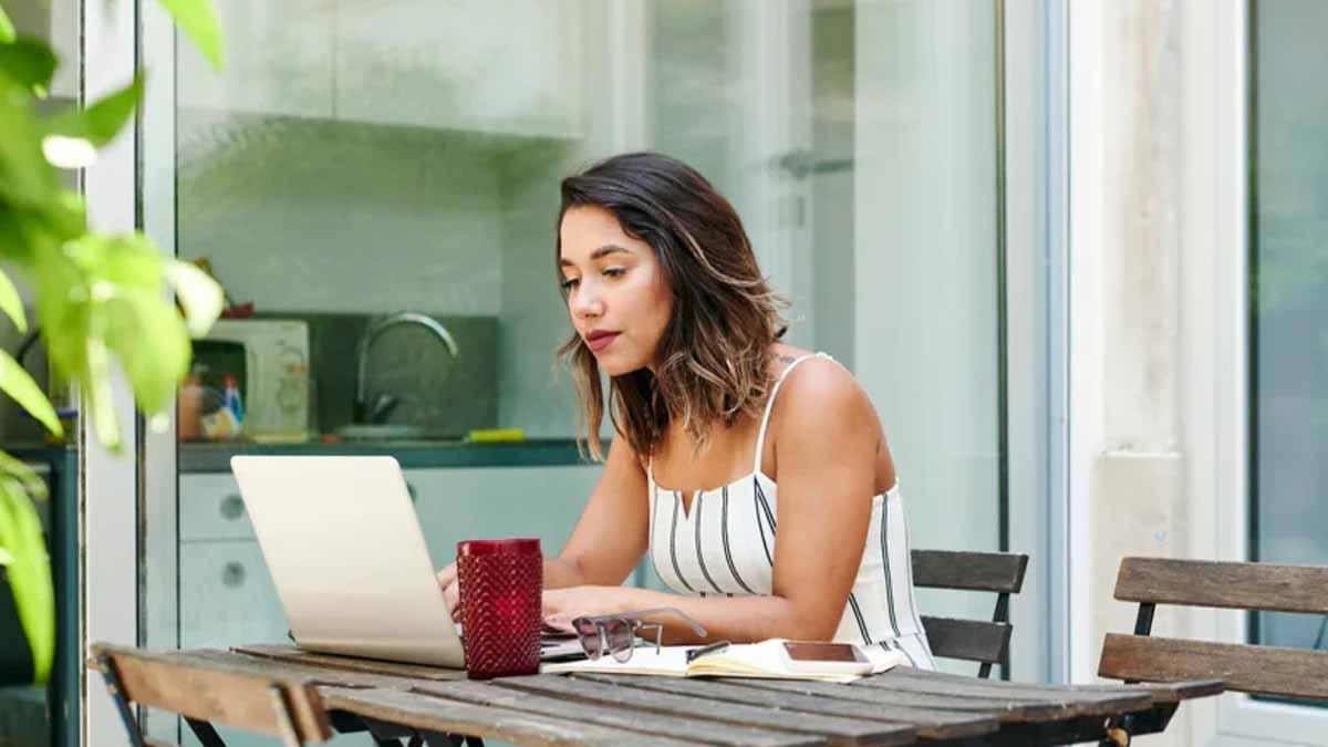 Woman at a table, casually working on a laptop