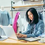 Eine Frau sitzt vor einen Laptop in einem Modegeschäft