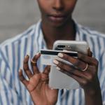 una mujer sostiene su móvil y tarjeta de crédito