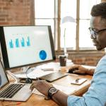 Hombre de oficina, sentado en un escritorio, explorando las últimas tendencias de atención al cliente en su ordenador portátil.