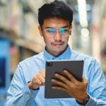 A man in glasses and a blue shirt uses a digital tablet for asset service management