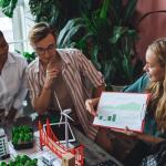 Three people looking at a pitch deck in an office around a model.