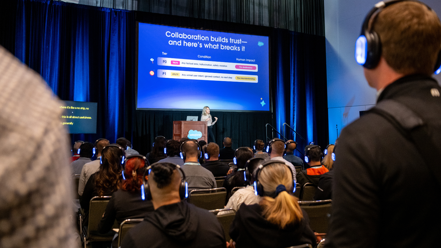 A speaker on stage at a Salesforce event presenting a slide about the common failures of AI agents to understand human context.