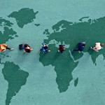 An illustration of six people walking across a large map of the world: global commerce expansion.