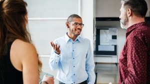 A business leader talking to two other employees.