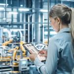 Woman in a factory, holding a tablet while reviewing field service metrics