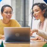 Salespeople using the BANT framework to ask questions of prospects while on a laptop, smiling.