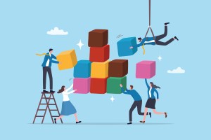 Cinq personnes collaborent pour construire une structure à partir de blocs colorés, l'une sur une échelle, une autre suspendue par une grue.