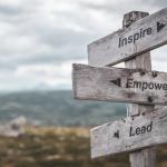 Wooden signpost showing inspire, empower and lead directions for business leadership development