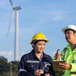 Two technicians in hard hats use technology to support field service sustainability.