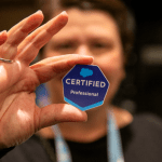 Photo of a man holding up a badge that says Certified Professional / Salesforce AI certification
