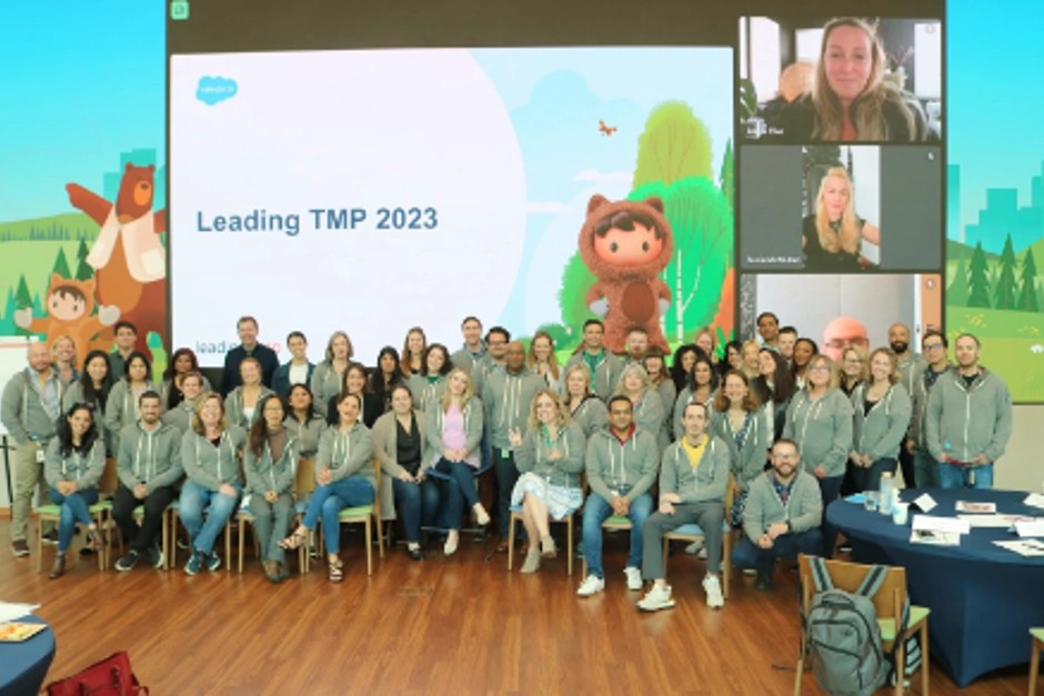 A group of Salesforce employees from Latam are posing in front of a screen that says: "Leading TMP 2023"