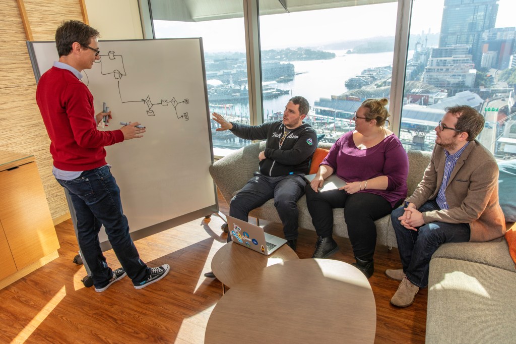 Salesforce Sydney employees whiteboard some ideas during a meeting.