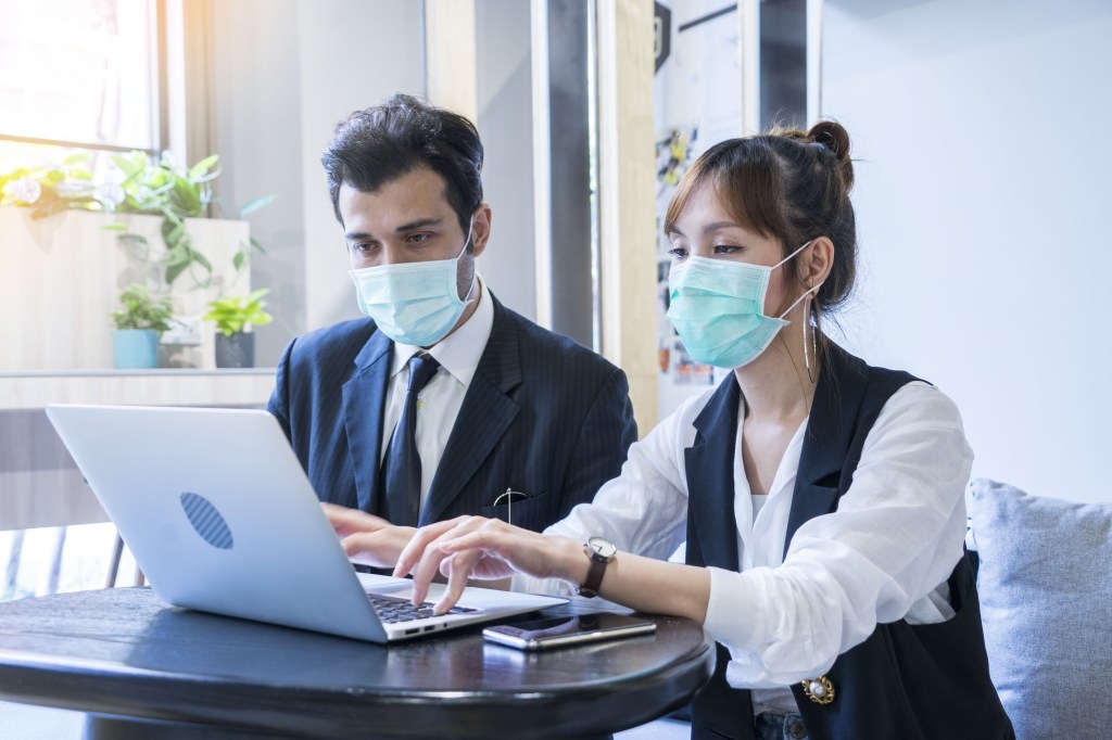 2 workers meeting together with laptop and wear protective masks