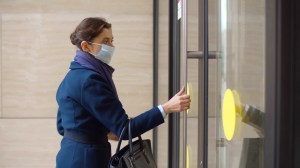 businesswoman putting on safety mask and entering office building